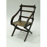 A circa 1900 child's oak ladder back elbow chair on X frame base,
