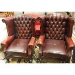 A pair of modern red leather upholstered wing back armchairs with button backs and scroll arms
