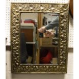 An early 20th Century bevelled mirror with embossed brass frame depicting shells