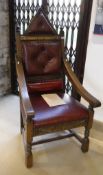 An oak chair in the gothic style with red buttoned leather back inscribed "Elizabeth II silver