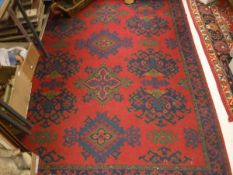 A Donegal style rug, the central panel with repeating medallions on a red ground,