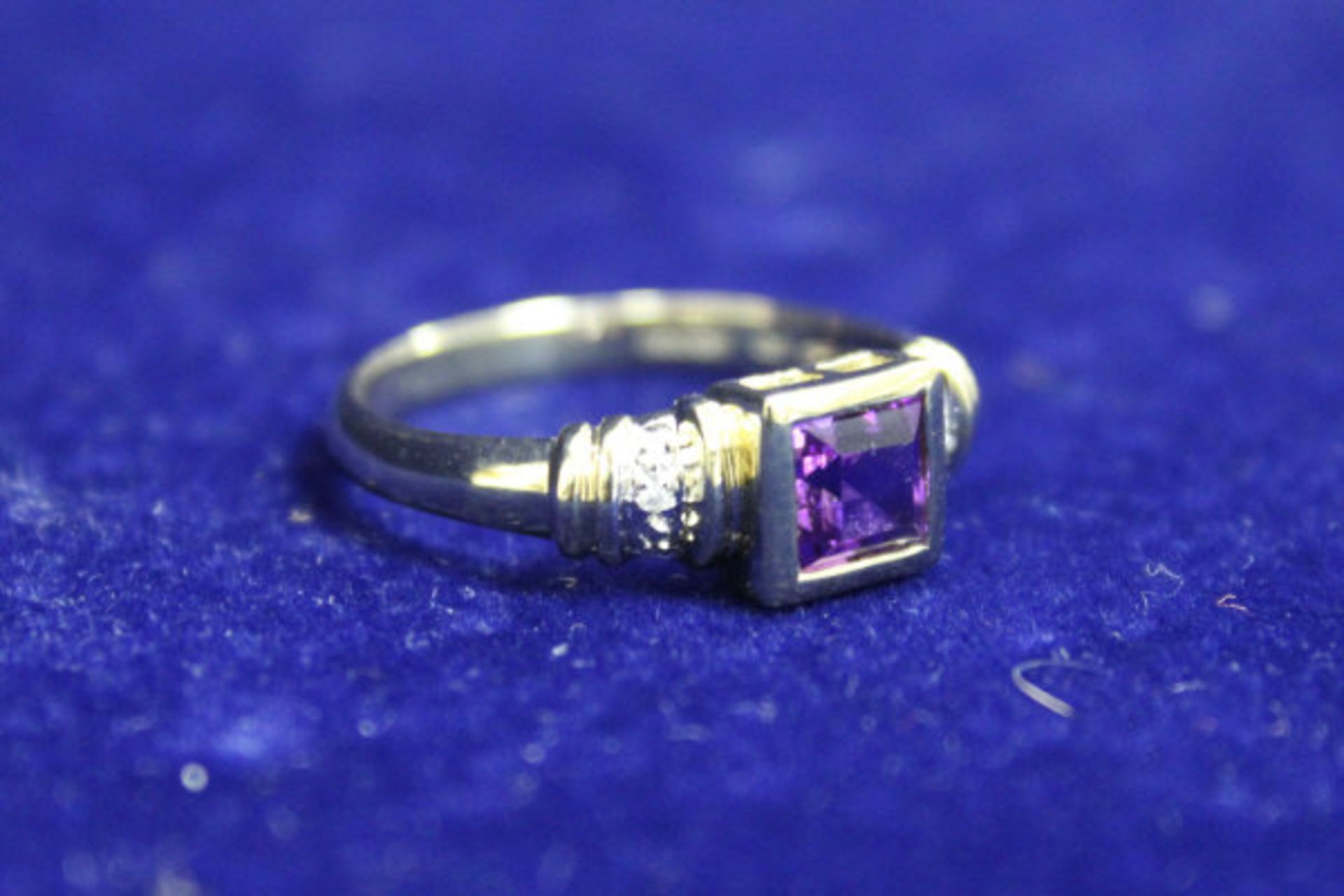 9ct gold ladies dress ring, the central square cut amethyst flanked by diamond set shoulders.