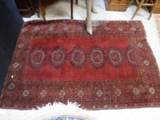 A Turkoman rug, the central panel set with repeating medallions on a dark red ground,