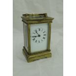 A lacquered brass cased carriage clock with white enamel dial and Roman numerals