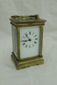 A lacquered brass cased carriage clock with white enamel dial and Roman numerals