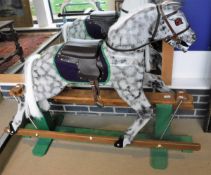 A 20th Century grey dapple painted rocking horse with leather effect and felt saddle on a green