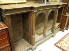 An oak break front bookcase with two arch glazed cabinet doors flanked with adjustable shelves on a
