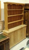 A modern pine dresser of three cupboard doors with an associated oak three tier plate rack