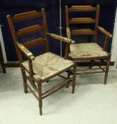 A pair of late 19th Century rush seated ladder back elbow chairs in the arts and crafts manner,