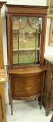 An Edwardian mahogany and inlaid display cabinet with single glazed door over a bow fronted