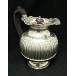 An Edwardian silver hot water jug of reeded form with gadrooned and foliate decorated rim (by