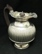 An Edwardian silver hot water jug of reeded form with gadrooned and foliate decorated rim (by