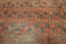 An Afghan carpet, the central panel set with repeating medallions on a dark red ground,