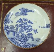 A Japanese blue and white charger decorated with coastal scene and building with brown-glazed