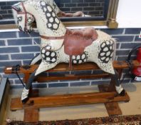 An early 20th Century painted rocking horse later dappled on a pine and wrought iron base