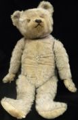 An early 20th Century silver plush wood wool filled bear with jointed arms and legs