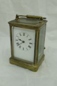 A circa 1900 lacquered brass cased carriage clock with white enamel dial and Roman numerals
