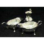 A pair of George III silver sauce boats on three paw feet with foliate decorated thumb piece (by