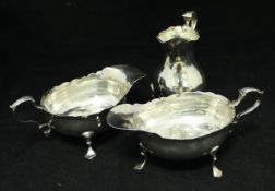 A pair of George III silver sauce boats on three paw feet with foliate decorated thumb piece (by