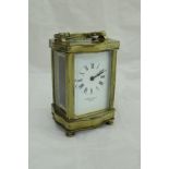 A lacquered brass cased carriage clock of serpentine form,