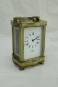 A lacquered brass cased carriage clock of serpentine form,