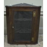 A George III mahogany hanging corner cabinet with shaped shelves and later glazed doors 'H' brass