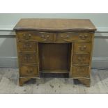 A mahogany kneehole desk of serpentine outline having two doors across and three small drawers to