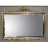 A reproduction gold painted plaster over mantel mirror in Adams style with engraved bevelled plate,