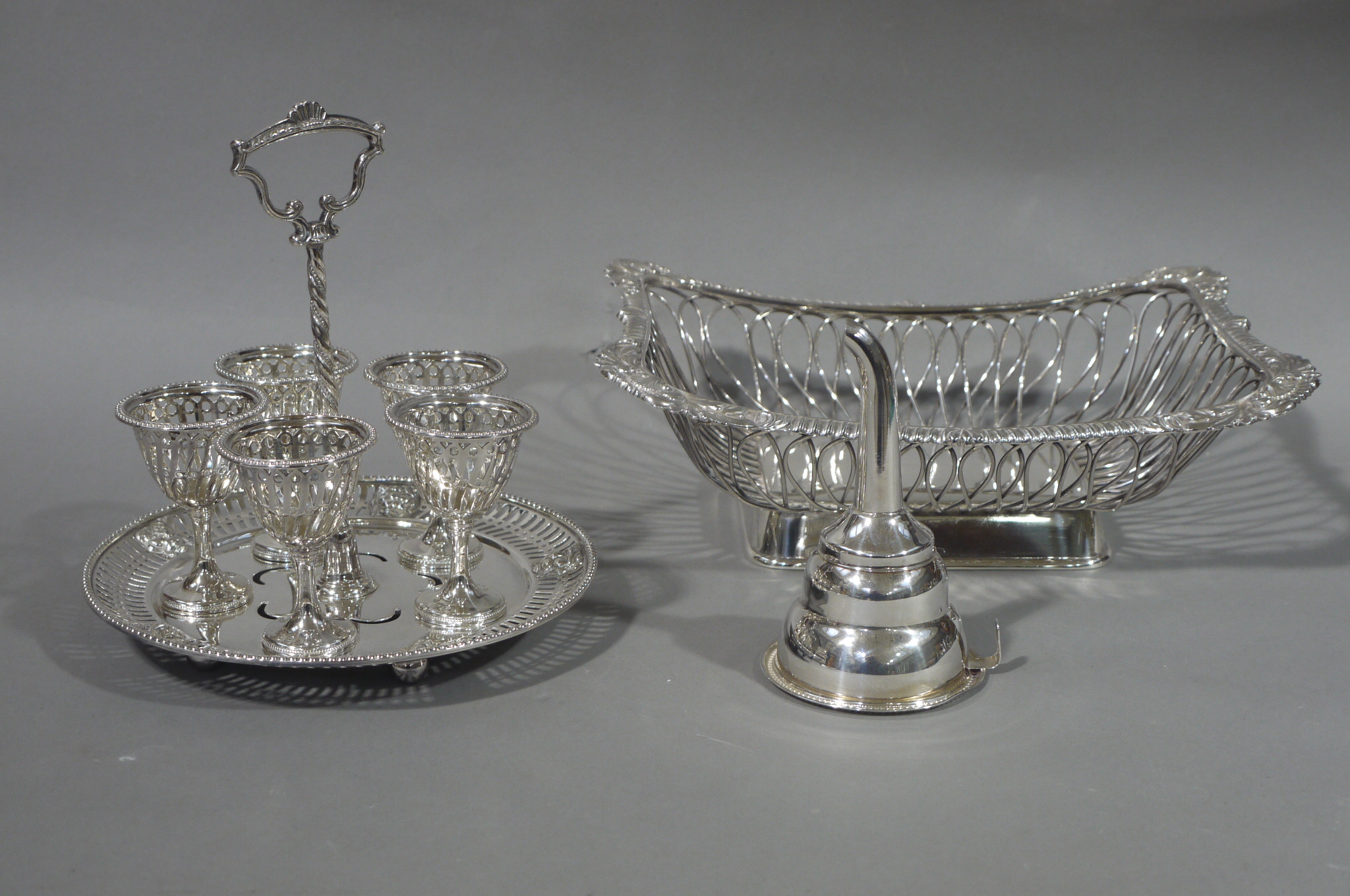 A silver plated egg cruet of five egg cups on a circular stand with pierced rim and ball feet,