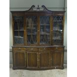 A George III style breakfront bookcase with pierced swan neck pediments centred on an urnular