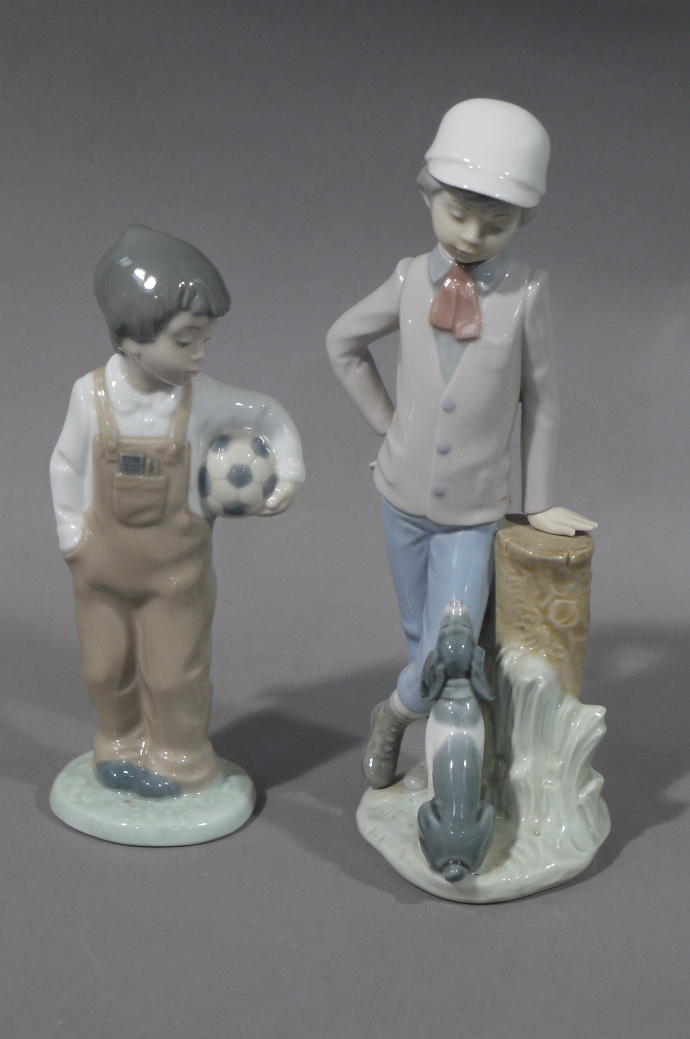 Two Nao figures of boy and dog beside a tree trunk,