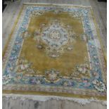 A Chinese washed wool sculpted carpet with central oval floral medallion on a mustard coloured