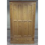 A reproduction pine wardrobe with flared cornice the pair of panelled doors flanked by fluted