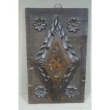 An oak panel applied with a lozenge shaped boss, gadroon rimmed and inlaid with stylised flowers,