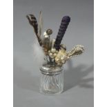 A collection of hat pins held in a silver lidded glass hair tidy