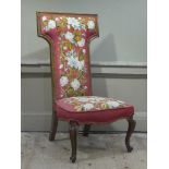 A Victorian walnut framed prie dieu chair having a floral pink ground tapestry upholstered back and