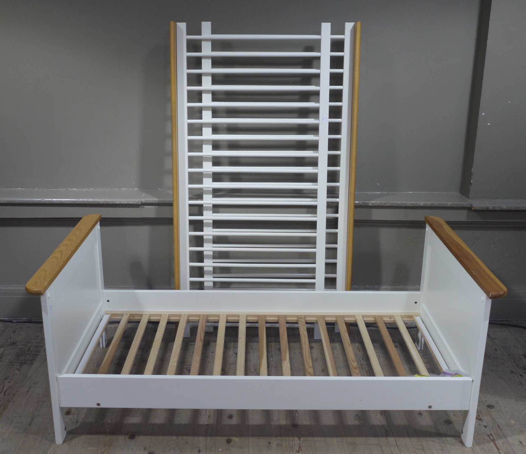 A child's cream painted and pine cot converting to a bed,
