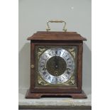 A reproduction mantel clock in George II style the pergola shaped top above a glazed door enclosing