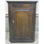 A George III oak hanging corner cupboard with flared cornice and raised fielded panelled door 106cm