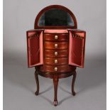 A mahogany finish D-shape jewellery cabinet having a lift up mirror lined top above an open