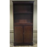 A mahogany bookshelf with flared cornice, adjustable shelf above a pair of figured doors,