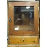 A stained pine small cabinet with glazed door above a drawer,