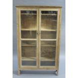 A pine book case enclosed by a pair of glazed doors, adjustable shelved interior,