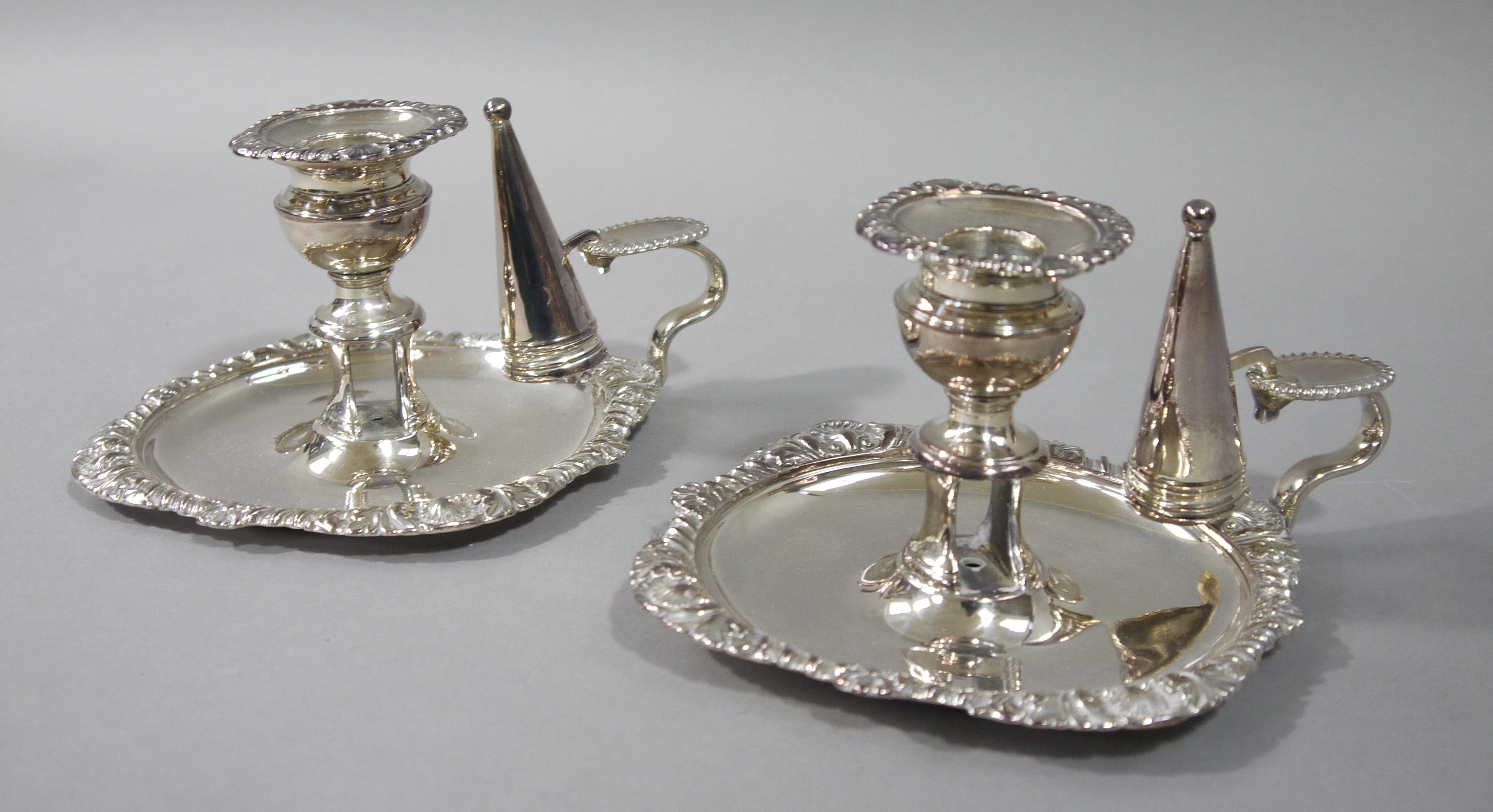 A pair of Victorian style silver plated chamber sticks with conical shaped snuffers,