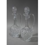 A pair of Edwardian cut glass ewers with tear shaped stoppers cut necks and bodies, star cut bases,