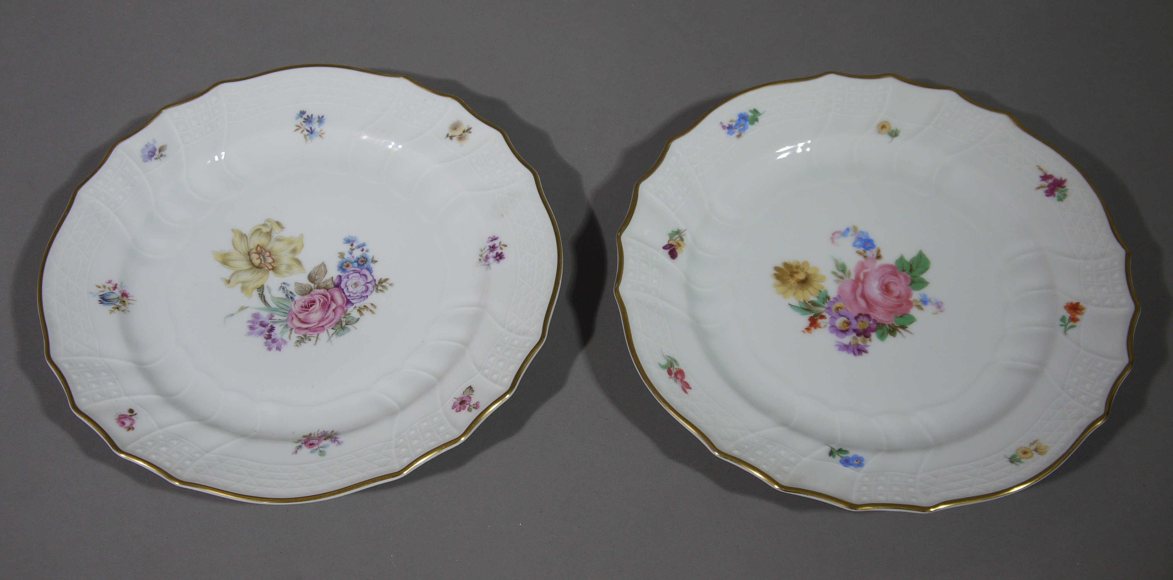 A pair of Hutschenreuther china plates, printed with floral sprays within a moulded and gilt border,