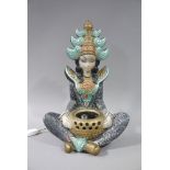 A plaster table lamp modelled as an Indonesian young woman seated cross legged with bowl in her lap,