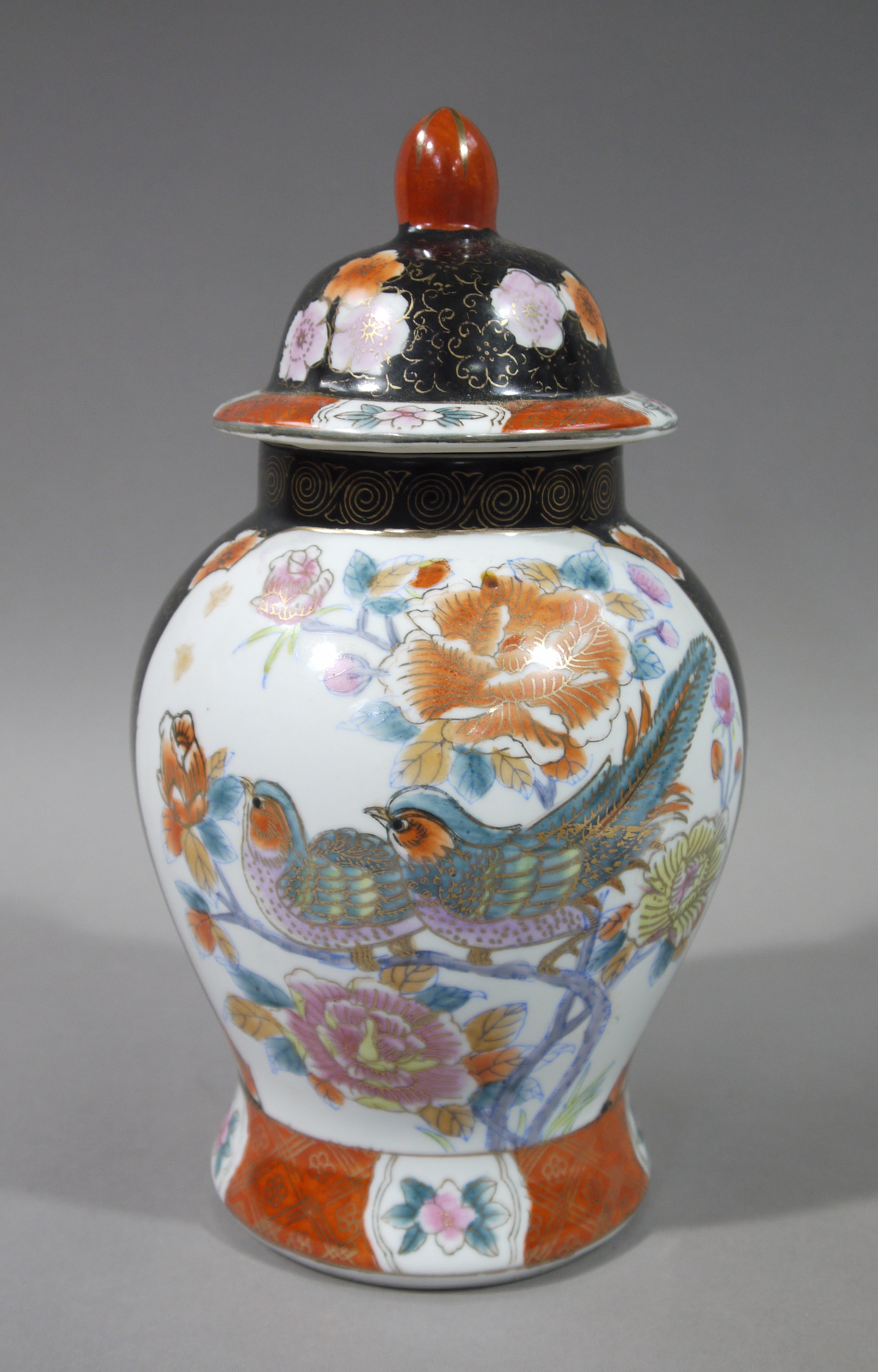 A Chinese baluster vase and cover painted with birds on flowering branches on a gilt scroll black