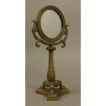 A BRONZE DRESSING TABLE MIRROR, the circular plate within a laurel cast frame, scrolling support,