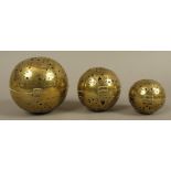 A SET OF THREE GRADUATED EASTERN BRASS SPHERICAL CENSERS, pierced and engraved overall,